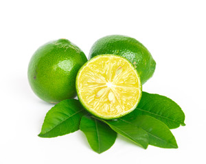 Two homegrown raw Asian limes with half cut slices and green leaves isolated on white