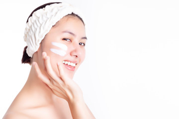 Asian woman apply cream, lotion to beautiful skin on cheek after bath. Young woman showing cream or moisturizer on face. Smiling Asia beautiful girl get happiness. She has nice skin. Skincare concept