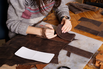 Girl makes leather purse.