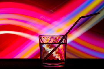 glass with a drink and a tube in club light.