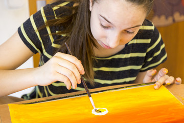 Ein Mädchen malt zu hause mit gelber farbe auf ein stück papier din A3