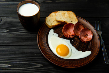 breakfast of scrambled eggs with sausage, bread and a glass of milk.