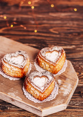 Tree homemade cupcakes in the form of a heart on white napkins on a wooden background. Close up, copy space.