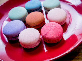 French colorful macarons on a red plate. Restaurant.
