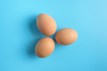 Three fresh brown chicken eggs on a blue background. Healthy good nutrition. Natural organic farm products.
