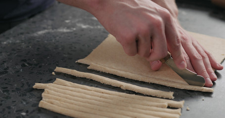 man cutting flat dough with knife