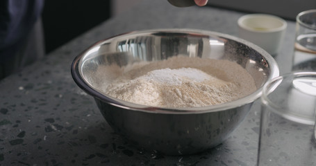 add dry ingredients into flour in steel bowl on concrete countertop