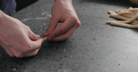 man making grissini on concretre countertop