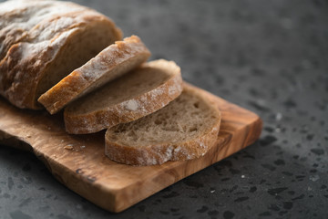 Sliced rustic style ciabatta with rye flour on olive board