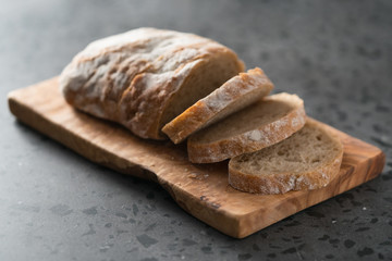 Sliced rustic style ciabatta with rye flour on olive board
