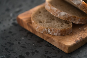 Sliced rustic style ciabatta with rye flour on olive board