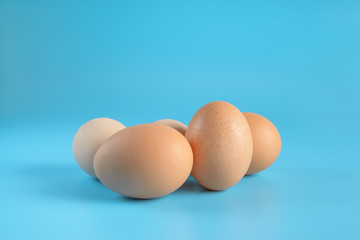 Five fresh brown chicken eggs on a blue background. Healthy good nutrition. Natural organic farm products.