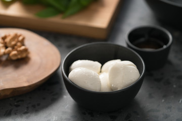 closeup small mozzarella balls in black bowl on concrete background