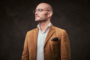 Successfull well-dressed mature bald businessman posing for camera in a dark studio wearing stylish...