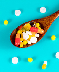 Wooden spoon full of pills, tablets, vitamins, drugs, omega 3 fish oil, gel capsules, medicament...