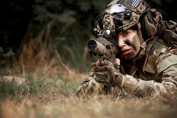 close up of woman soldier holding gun laying on the ground