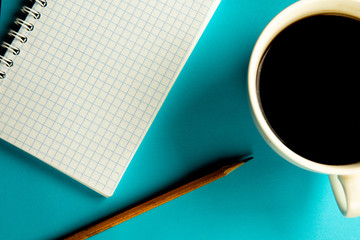 notebook, pencil and cup of coffee on a blue background.