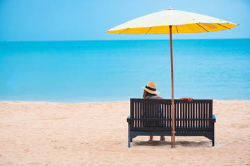 Woman with straw hat relaxing on the beach.