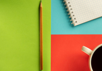 notebook, pencil and cup of coffee on a multi-colored background.