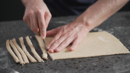 man cutting flat dough with knife