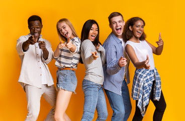 Cheerful multiracial group of students indicating at camera