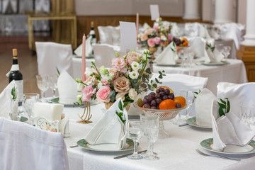 A beautiful flower arrangement in a Golden vase stands on the holiday table. A Golden candlestick with a pink candle