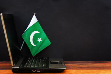  flag of Pakistan , computer, laptop on table and dark background