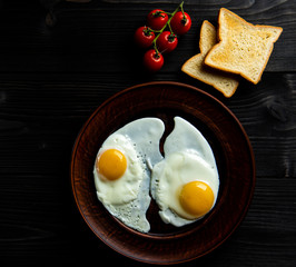 breakfast of scrambled eggs with fresh tomatoes and two slices of bread on a dark background.