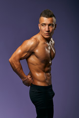 Fototapeta premium serious handsome athlete keeping his arms behind his back posing to the camera, close up portrait, isolated blue background, studio shot