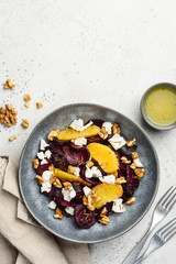 Healthy salad with baked beetroots, feta cheese, oranges, walnuts and caraway seeds in a blue bowl. Top view. Copy space