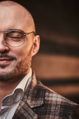 Obraz premium Fashionable and calm bald businessman posing with closed eyes for camera in a studio wearing chic checkered wool jacket, white shirt and glasses