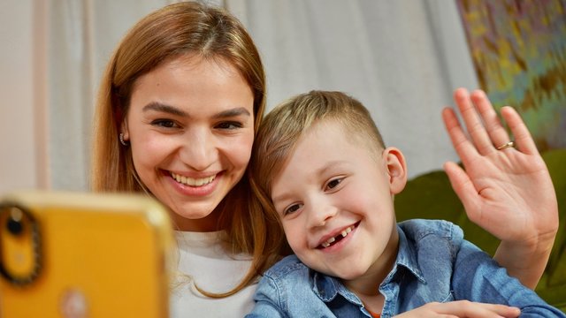 Beautiful mom and son making selfie at home. Happy family having a facetime video call. Unity, connection, technology concept