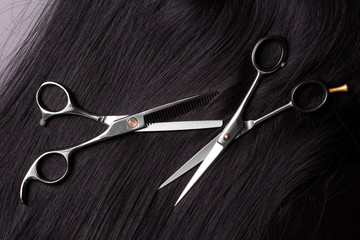 Barber scissors close-up. Black hair and a pair of professional scissors for a hairdresser.