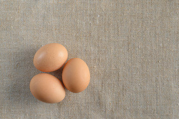 Three fresh brown chicken eggs on a canvas background. Healthy good nutrition. Natural organic farm products.
