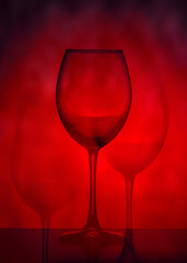 Wine glasses on a red background. Abstraction. Multiple exposure of wine glasses. Bifurcation effect. 