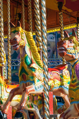 Fototapeta na wymiar Brightly coloured carousel horses at fairground.