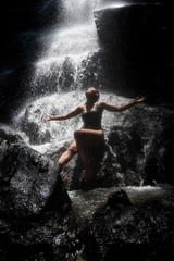 Obraz premium young attractive and blissful Asian Indonesian woman overwhelmed by the beauty of natural waterfall in tropical jungle enjoying happy the amazing and exotic travel destination