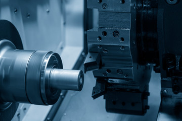 The CNC lathe machine in metal working process cutting the metal shaft parts with in the light blue...