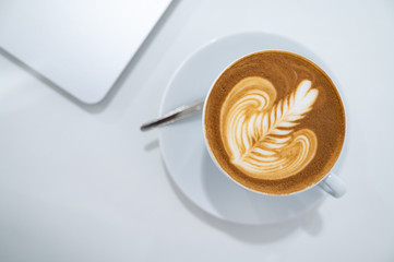 Close up of Latte art coffee cup with laptop computer flat lay