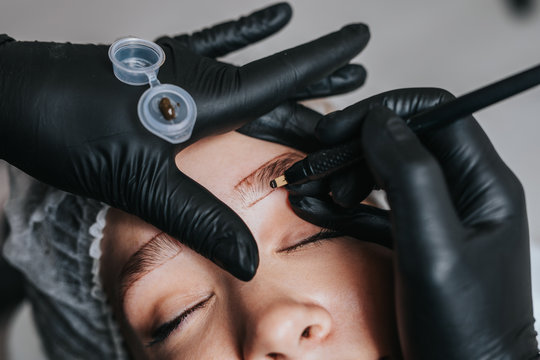 Eyebrows microblading concept. Cosmetologist preparing young woman for eyebrow permanent makeup procedure.