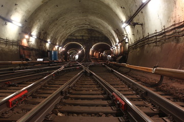 The illuminated tunnel. Crossing the subway railway. The train stands at the station. The illuminated tunnel with the metro track development.