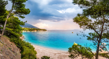 Coast near Zlatni Rat or Golden Horn beach in Bol town on Brac Island, Croatia with pine trees and turquoise sea water