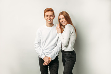 happy caucasian red haired boy and girl in white shirts stand posing isolated on white background. emotional smiling young people stand together and look at camera.