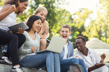 Group of international students celebrating success, checking exam results online