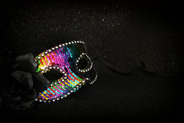 Photo of elegant and delicate colorful sequins Venetian mask over dark glitter background