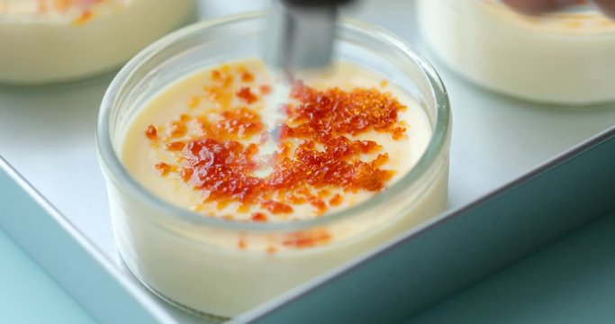 Caramelizing sugar on the top of creme brulee dessert using gas torch
