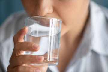 Young woman drinking pure mineral water from glass