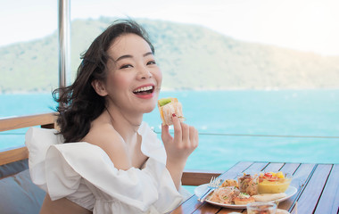 Beautiful woman is having breakfast beside blue sea