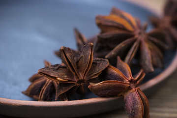 star anise with and without seeds, in a clay dish on a light wooden surface. spice for the recipe. beautiful picture, background.