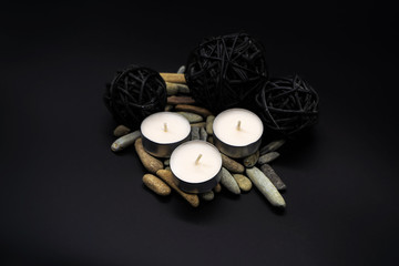 Velas acompañadas de adornos y piedras en fondo negro